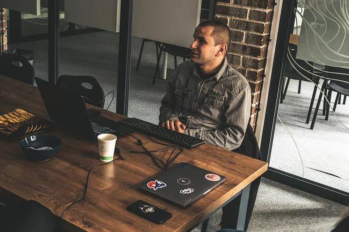 Przemek, sits by the desk in front of the computer while testing software.